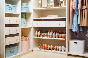 Large wardrobe with stylish women's clothing, shoes, accessories and boxes. Organization of storage space and fashion concept.