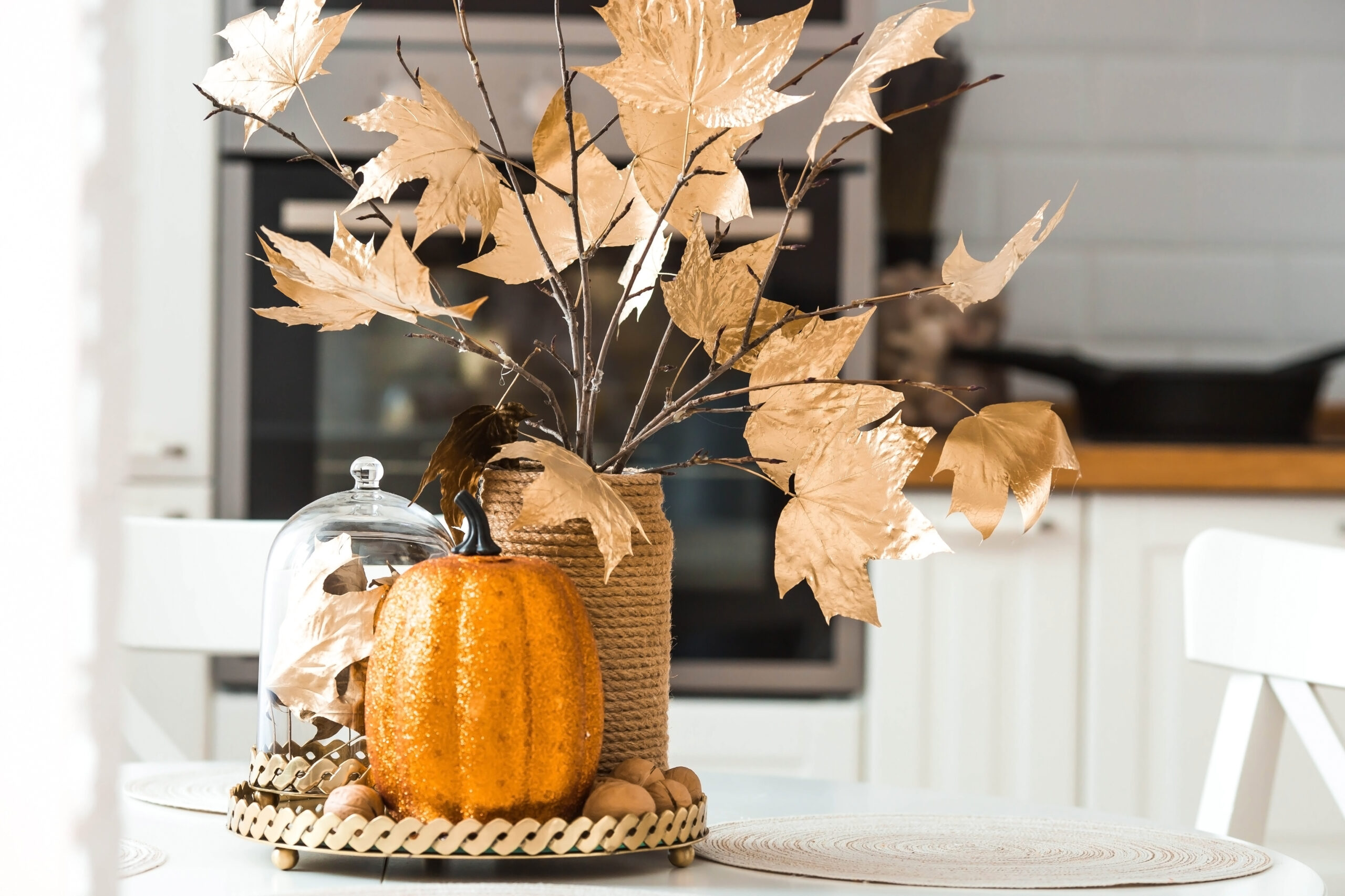 Branches with Golden leaves and a pumpkin on a tray. In the back