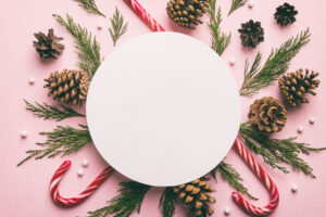 Flat lay Christmas composition. Round Paper blank, pine tree branches, christmas decorations on Colored background. Top view, copy space for text.